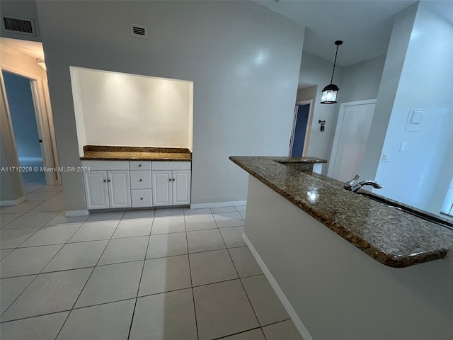 kitchen with white cabinets, decorative light fixtures, dark stone countertops, and light tile patterned floors