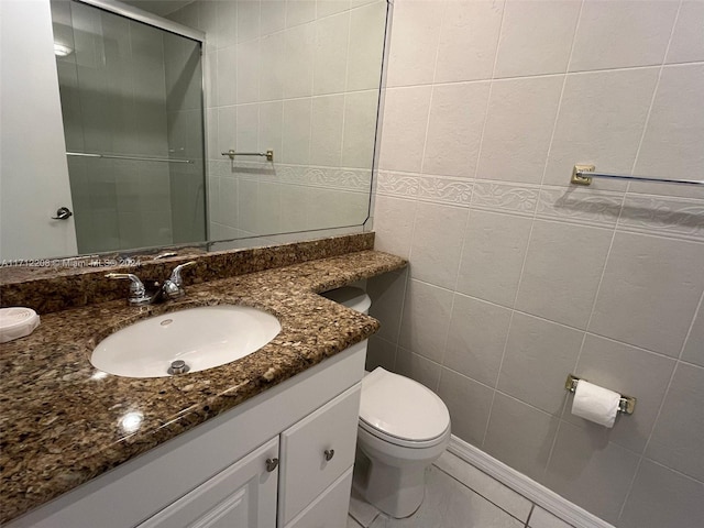 bathroom with tile patterned floors, vanity, tile walls, and toilet