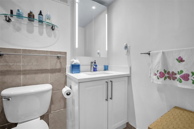 bathroom featuring vanity, toilet, and tile walls