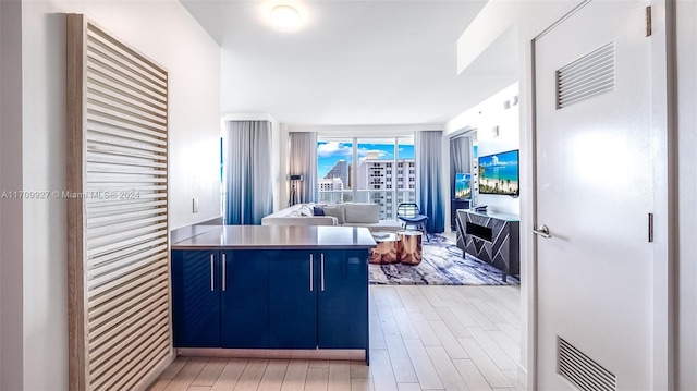 kitchen with kitchen peninsula, blue cabinetry, and light hardwood / wood-style flooring