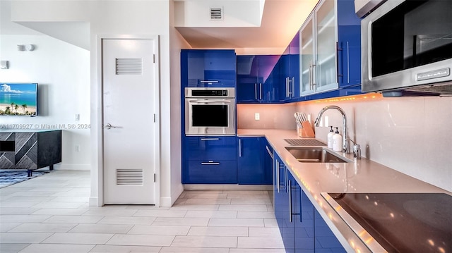 kitchen with decorative backsplash, appliances with stainless steel finishes, sink, blue cabinetry, and light tile patterned floors