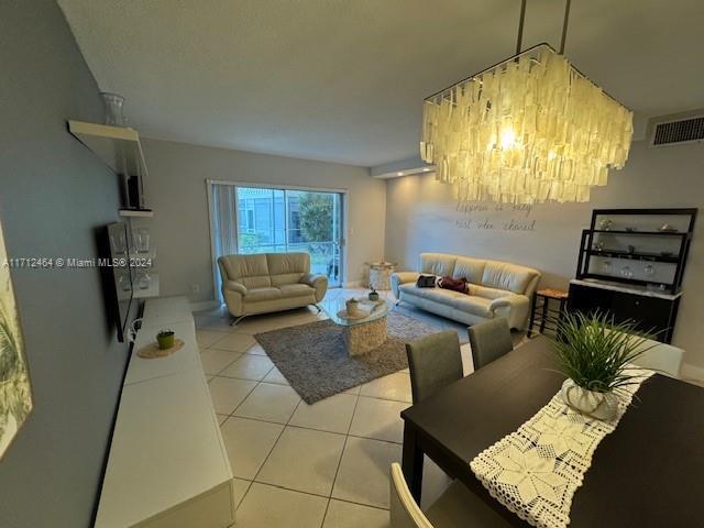 tiled living room with a notable chandelier