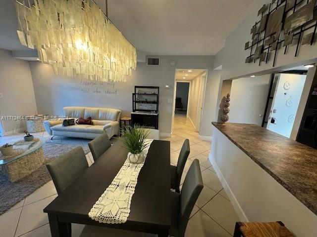 dining area featuring light tile patterned floors and a notable chandelier