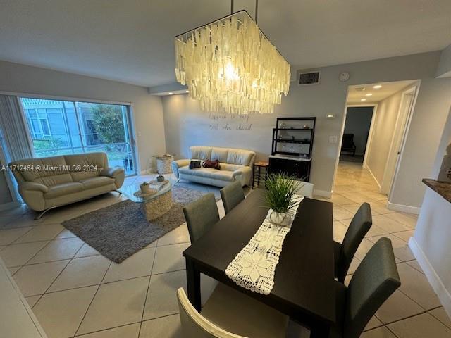 dining area with light tile patterned floors and an inviting chandelier