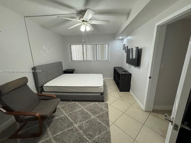 bedroom with a textured ceiling, ceiling fan, and light tile patterned flooring