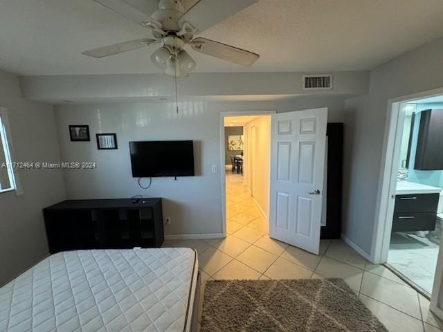 unfurnished bedroom with ensuite bath, ceiling fan, and light tile patterned flooring