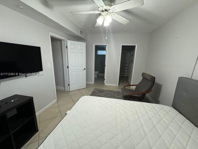 tiled bedroom with ceiling fan and a spacious closet