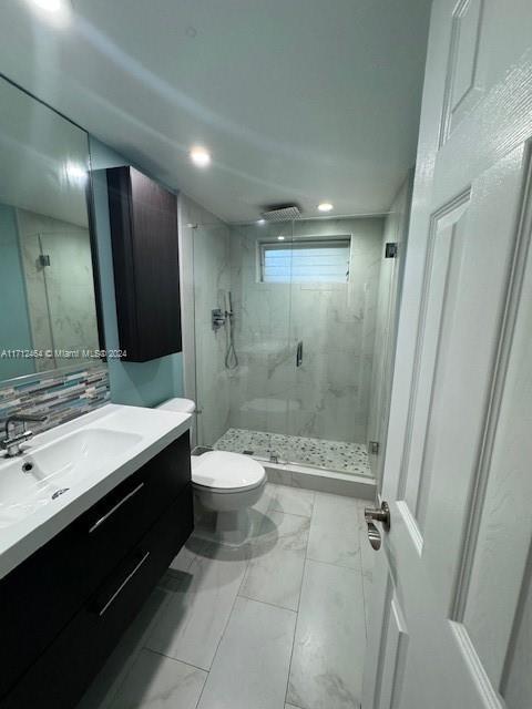 450 Golden Isles Dr Unit 1C, Hallandale Beach, FL 33009 - bathroom featuring marble look tile flooring, a shower stall, vanity, backsplash, and recessed lighting