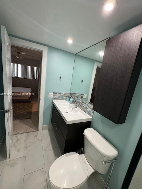 450 Golden Isles Dr Unit 1C, Hallandale Beach, FL 33009 - ensuite bathroom with vanity, marble finish floors, recessed lighting, decorative backsplash, and ceiling fan