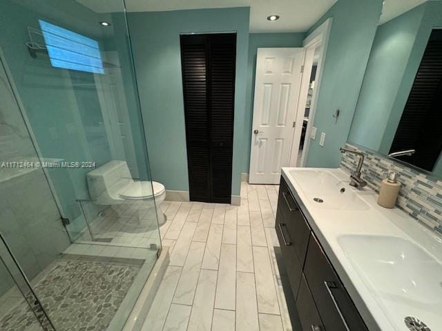 450 Golden Isles Dr Unit 1C, Hallandale Beach, FL 33009 - full bath with a closet, a shower stall, double vanity, tasteful backsplash, and wood finished floors