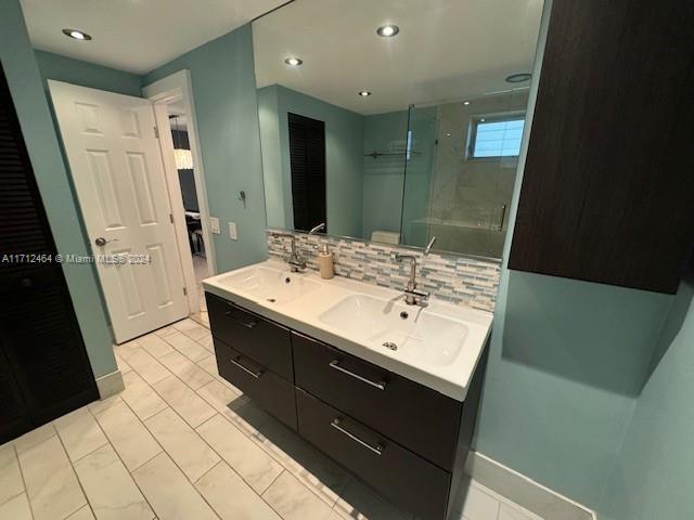 bathroom with backsplash, tile patterned flooring, vanity, and walk in shower