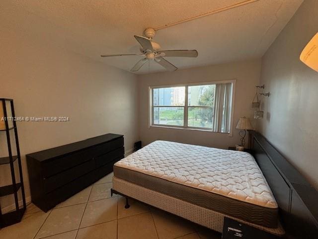 bedroom with ceiling fan, light tile patterned flooring, and a textured ceiling