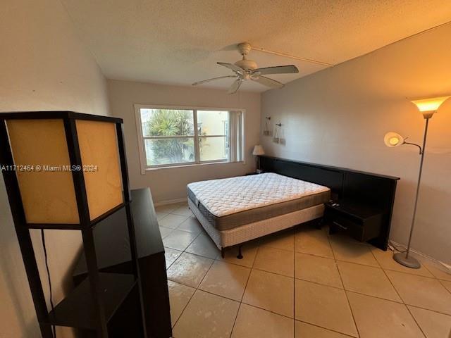 bedroom featuring light tile patterned floors, a textured ceiling, and ceiling fan