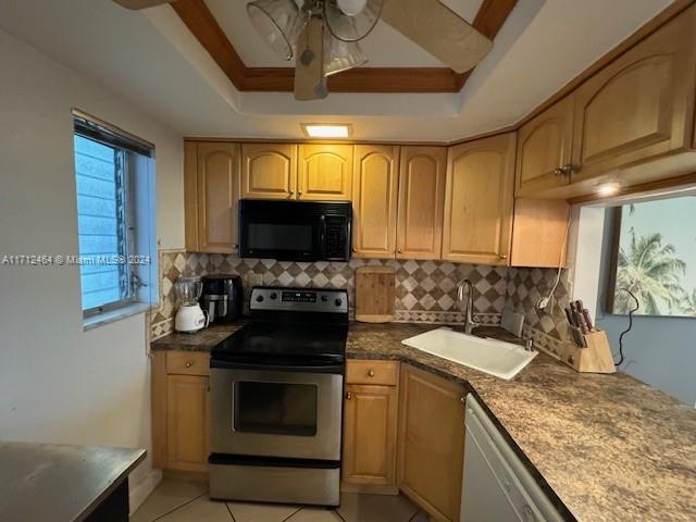 450 Golden Isles Dr Unit 1C, Hallandale Beach, FL 33009 - kitchen with electric range, black microwave, a raised ceiling, white dishwasher, and decorative backsplash