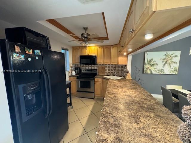 kitchen featuring black appliances, decorative backsplash, ceiling fan, light tile patterned floors, and a tray ceiling