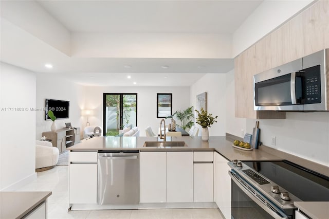 kitchen with kitchen peninsula, light brown cabinetry, stainless steel appliances, sink, and light tile patterned floors