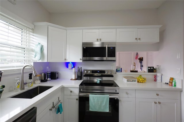 kitchen featuring stainless steel appliances, white cabinetry, and sink