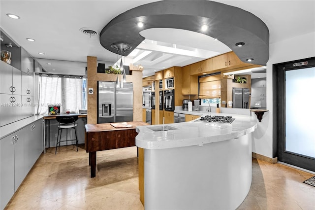 kitchen featuring kitchen peninsula, appliances with stainless steel finishes, sink, beamed ceiling, and hanging light fixtures