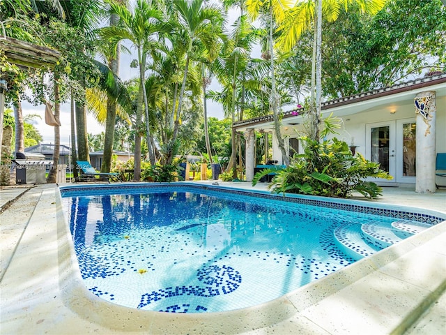 view of swimming pool featuring french doors, a patio, and area for grilling