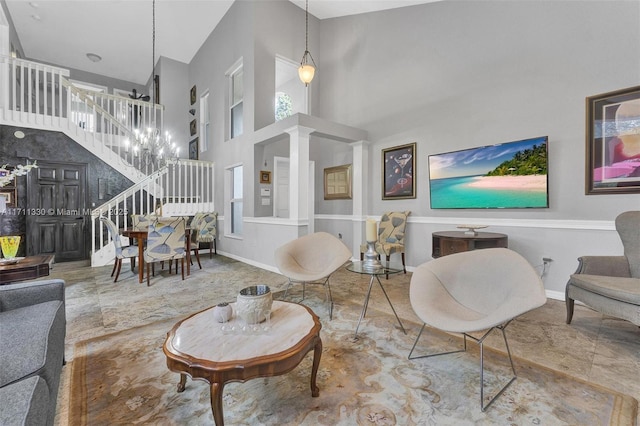 living room featuring a towering ceiling, a chandelier, and ornate columns