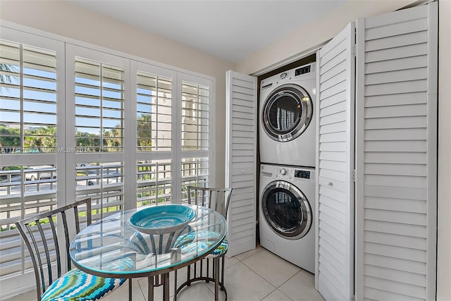 clothes washing area featuring a healthy amount of sunlight, light tile patterned floors, and stacked washer / dryer