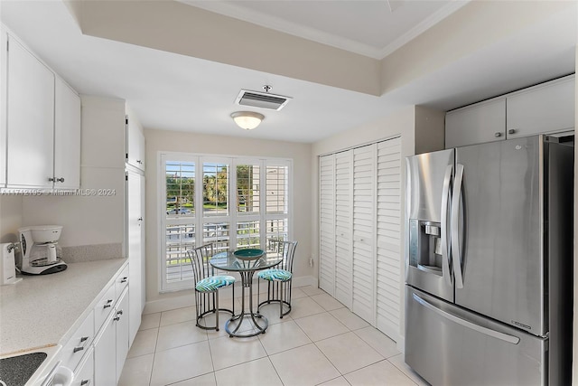 kitchen featuring white cabinets, stainless steel fridge with ice dispenser, light tile patterned floors, and range