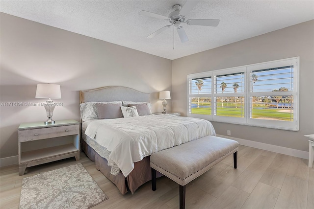 bedroom with a textured ceiling, light wood-type flooring, and ceiling fan