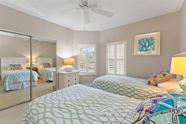 bedroom with ceiling fan, light wood-type flooring, a textured ceiling, and a closet