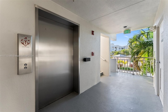 hallway featuring a textured ceiling and elevator