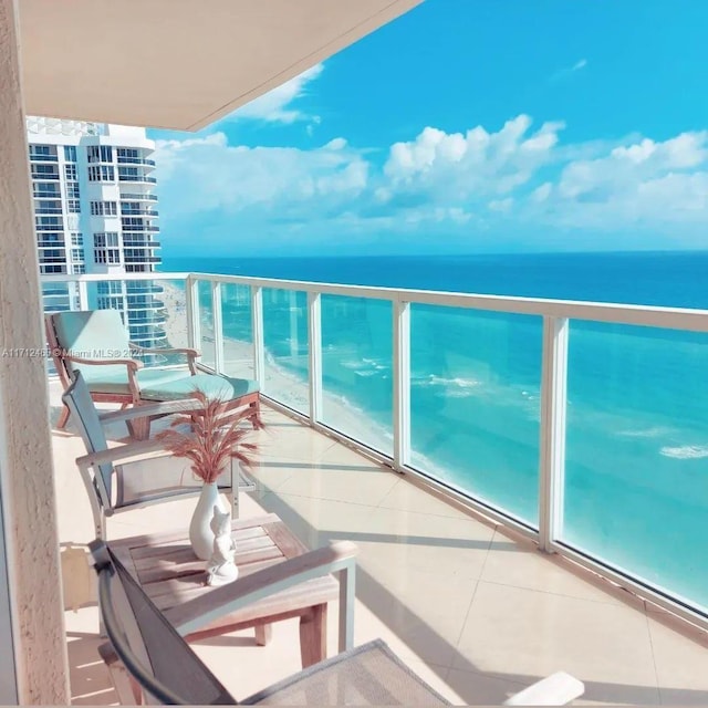 balcony with a water view and a view of the beach