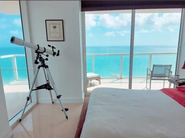 bedroom with light tile patterned floors, a water view, and multiple windows