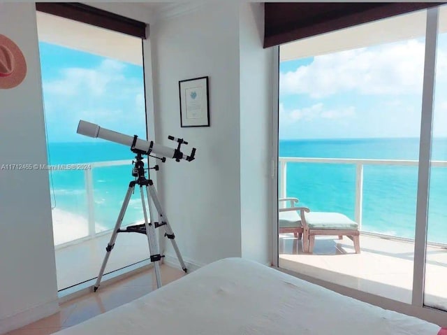 bedroom featuring multiple windows, a water view, and a view of the beach