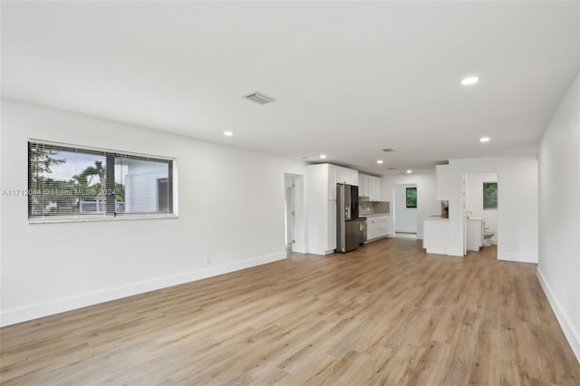 unfurnished living room featuring light wood-type flooring and a wealth of natural light