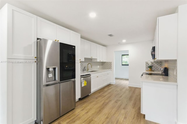 kitchen featuring white cabinets, appliances with stainless steel finishes, light wood-type flooring, and sink