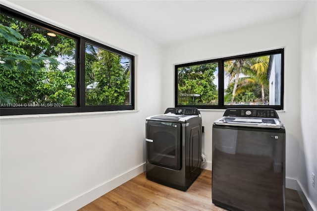 laundry room with washing machine and clothes dryer and light hardwood / wood-style floors