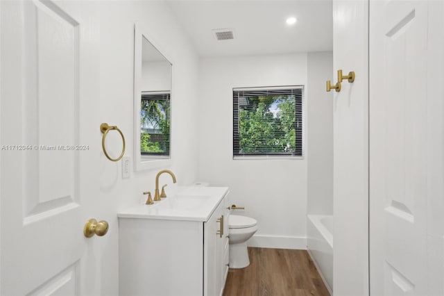 full bathroom with wood-type flooring, vanity, toilet, and a wealth of natural light