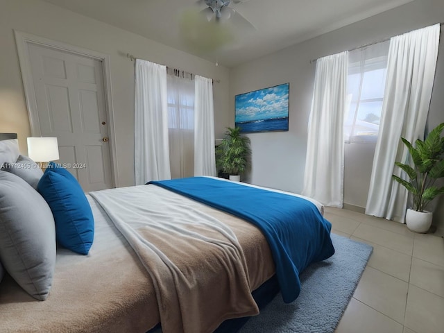 tiled bedroom featuring multiple windows and ceiling fan