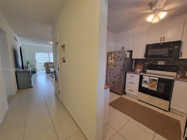 kitchen featuring stainless steel fridge, white electric range, white cabinets, and light tile patterned floors