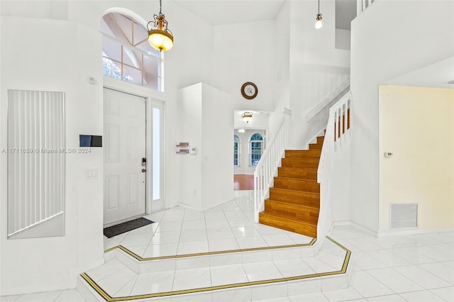 entrance foyer featuring a notable chandelier, light tile patterned flooring, and a high ceiling