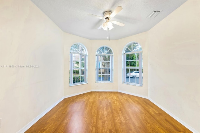 empty room featuring ceiling fan, a textured ceiling, and light hardwood / wood-style flooring