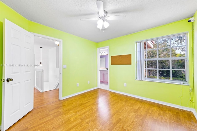 empty room with ceiling fan, a textured ceiling, and light hardwood / wood-style flooring