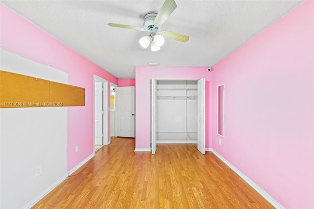 unfurnished bedroom with ceiling fan, a closet, a textured ceiling, and light hardwood / wood-style flooring