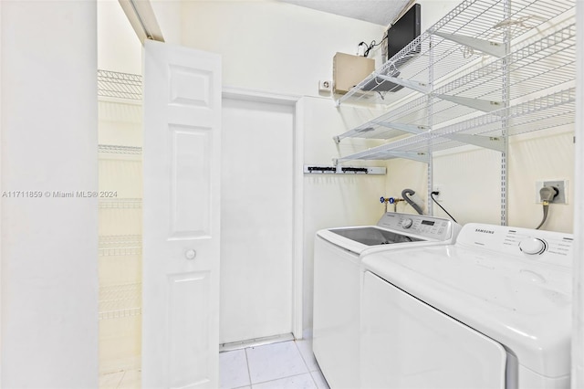 clothes washing area featuring washer and dryer and light tile patterned flooring