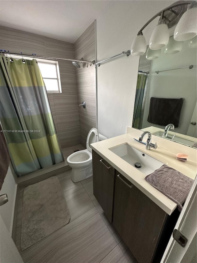 bathroom with a shower with shower curtain, vanity, toilet, and tile patterned flooring