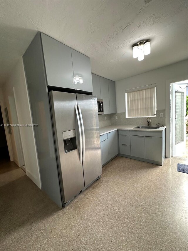 kitchen featuring gray cabinetry, sink, stainless steel appliances, and a textured ceiling