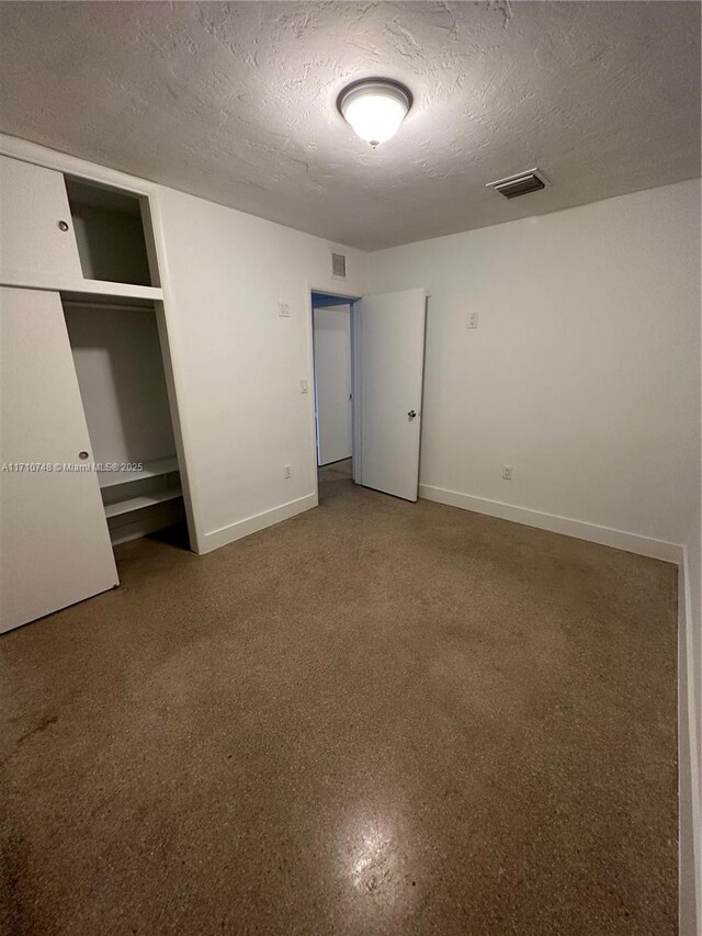 unfurnished bedroom with a textured ceiling and a closet