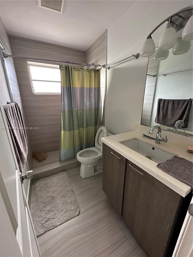 bathroom featuring vanity, curtained shower, and toilet