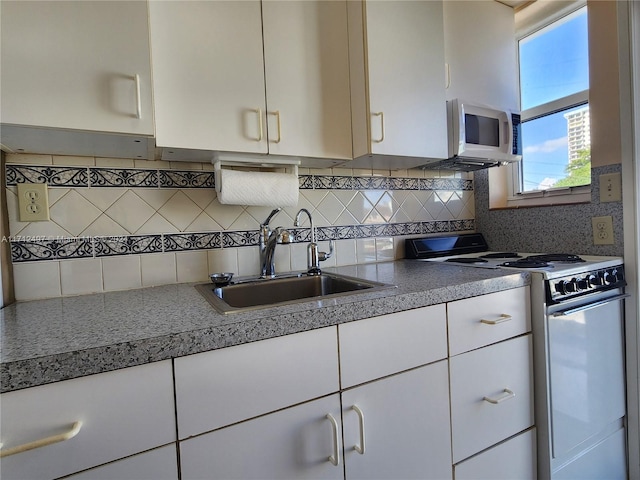 kitchen featuring decorative backsplash, white appliances, white cabinetry, and sink