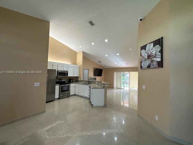 kitchen featuring vaulted ceiling, kitchen peninsula, light stone countertops, appliances with stainless steel finishes, and white cabinets