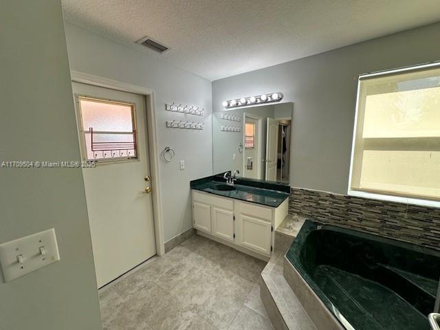 bathroom with vanity, a washtub, and a textured ceiling